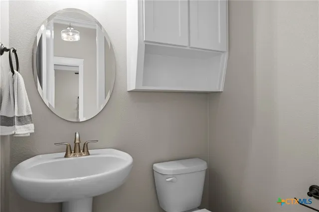 a bathroom with a toilet a sink and mirror