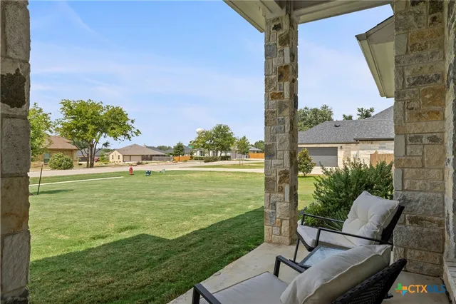 a view of a patio with lawn chairs floor to ceiling window and yard