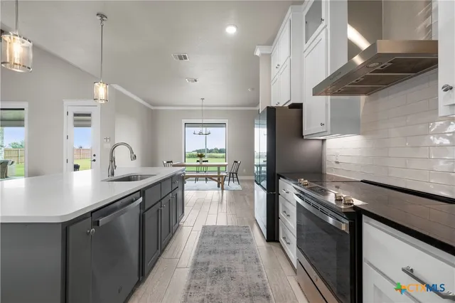 a kitchen with stainless steel appliances granite countertop a sink a stove and a refrigerator