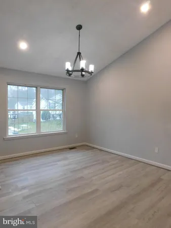 an empty room with wooden floor chandelier and windows