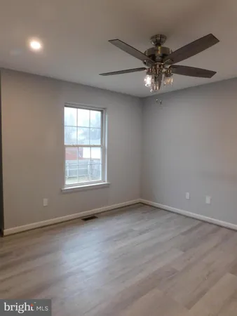 an empty room with wooden floor chandelier fan and windows