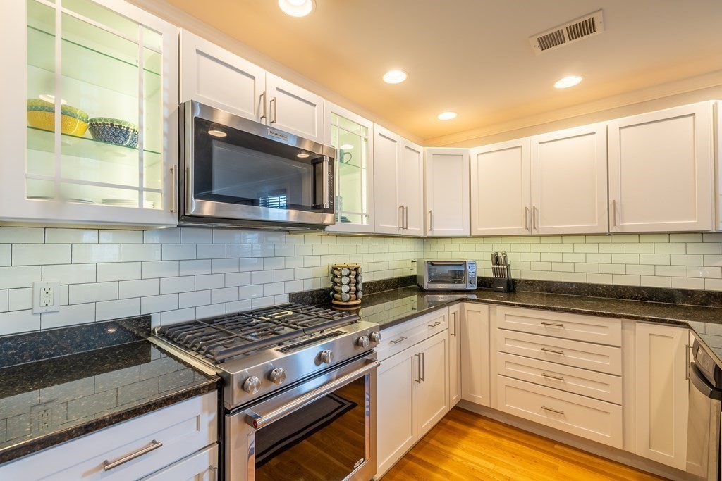 75 Main Street, Unit 102 Amesbury, MA 01913 - Photo 4 of 28 a kitchen with granite countertop a stove sink and cabinets
