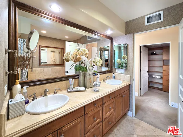 a bathroom with double vanity sinks a vanity and a large mirror