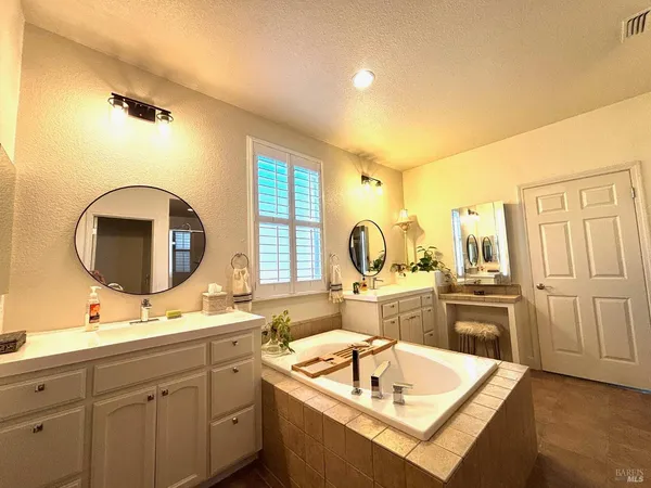 a bathroom with a double vanity sink mirror and bathtub