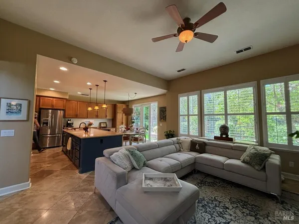 a living room with furniture ceiling fan and a large window