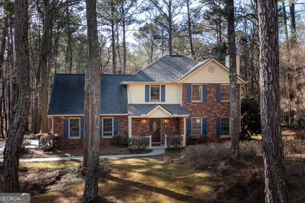 a front view of a house with yard tree and parking