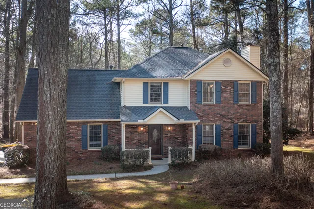 a front view of a house with yard and trees in the background