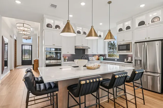 a kitchen with stainless steel appliances granite countertop a kitchen island a stove a table and chairs