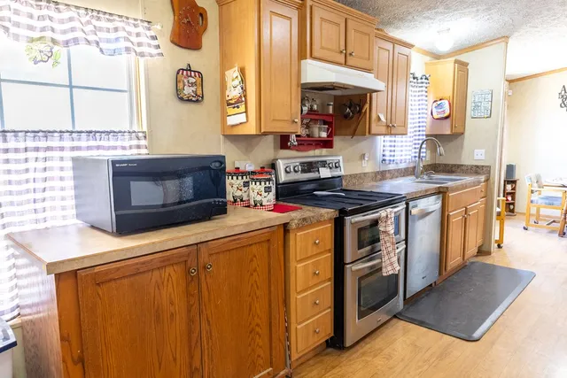 a kitchen with stainless steel appliances a stove a microwave a sink and cabinets