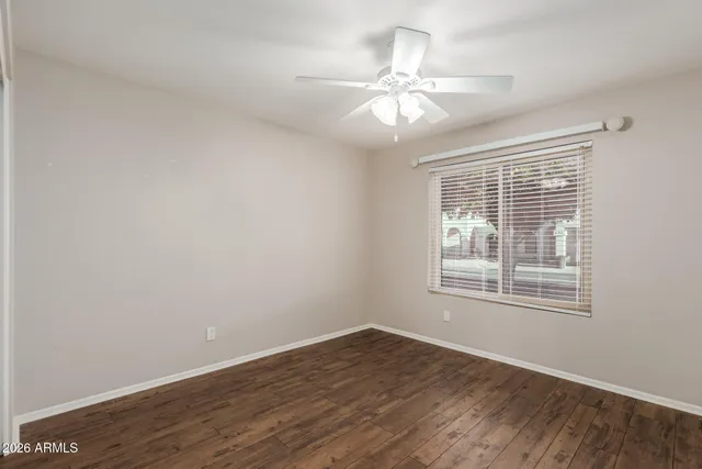 an empty room with wooden floor fan and windows