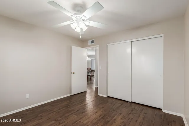 an empty room with wooden floor and ceiling fan
