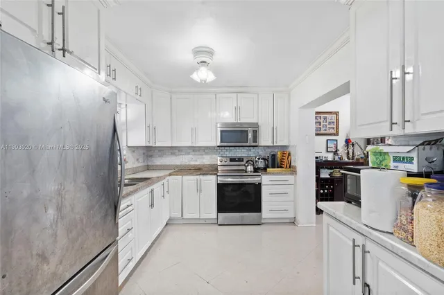 a kitchen with stainless steel appliances granite countertop a refrigerator a stove oven a sink dishwasher and white cabinets with wooden floor