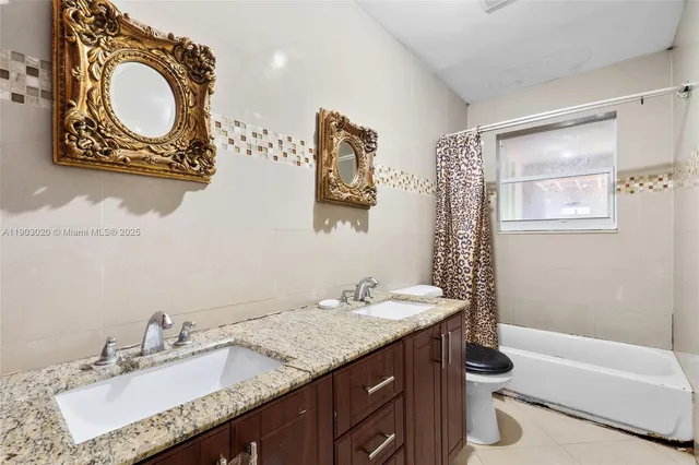 a bathroom with a granite countertop sink mirror toilet and bathtub