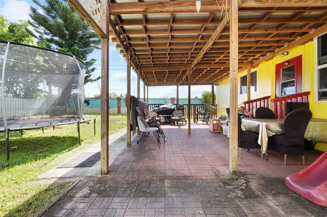 a view of a patio with table and chairs potted plants and a large tree
