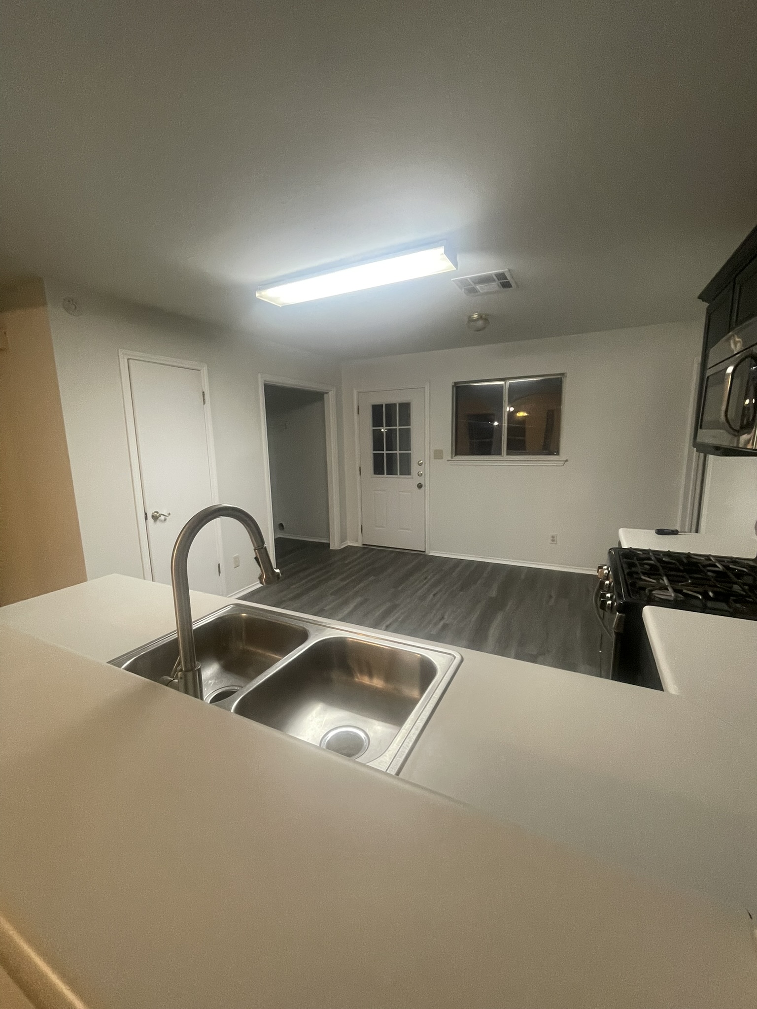 221 Britni Loop Kyle, TX 78640 - Photo 11 of 20 Kitchen with light countertops, stainless steel microwave, black range with gas stovetop, and dark wood-style flooring