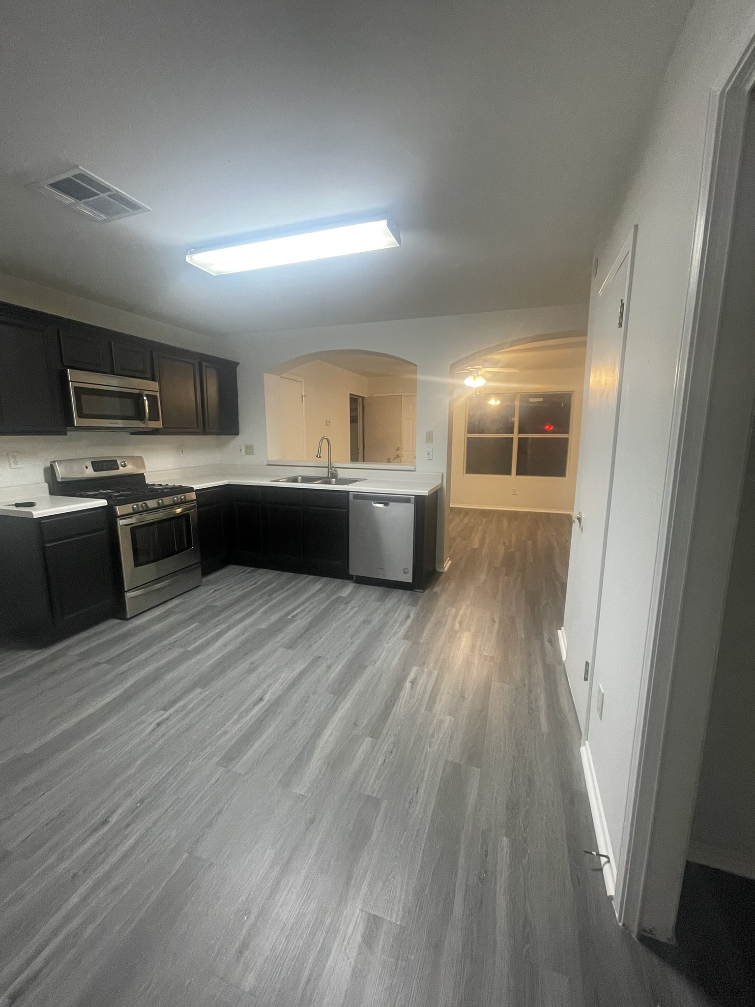 221 Britni Loop Kyle, TX 78640 - Photo 12 of 20 Kitchen with stainless steel appliances, light countertops, arched walkways, and dark wood-style floors