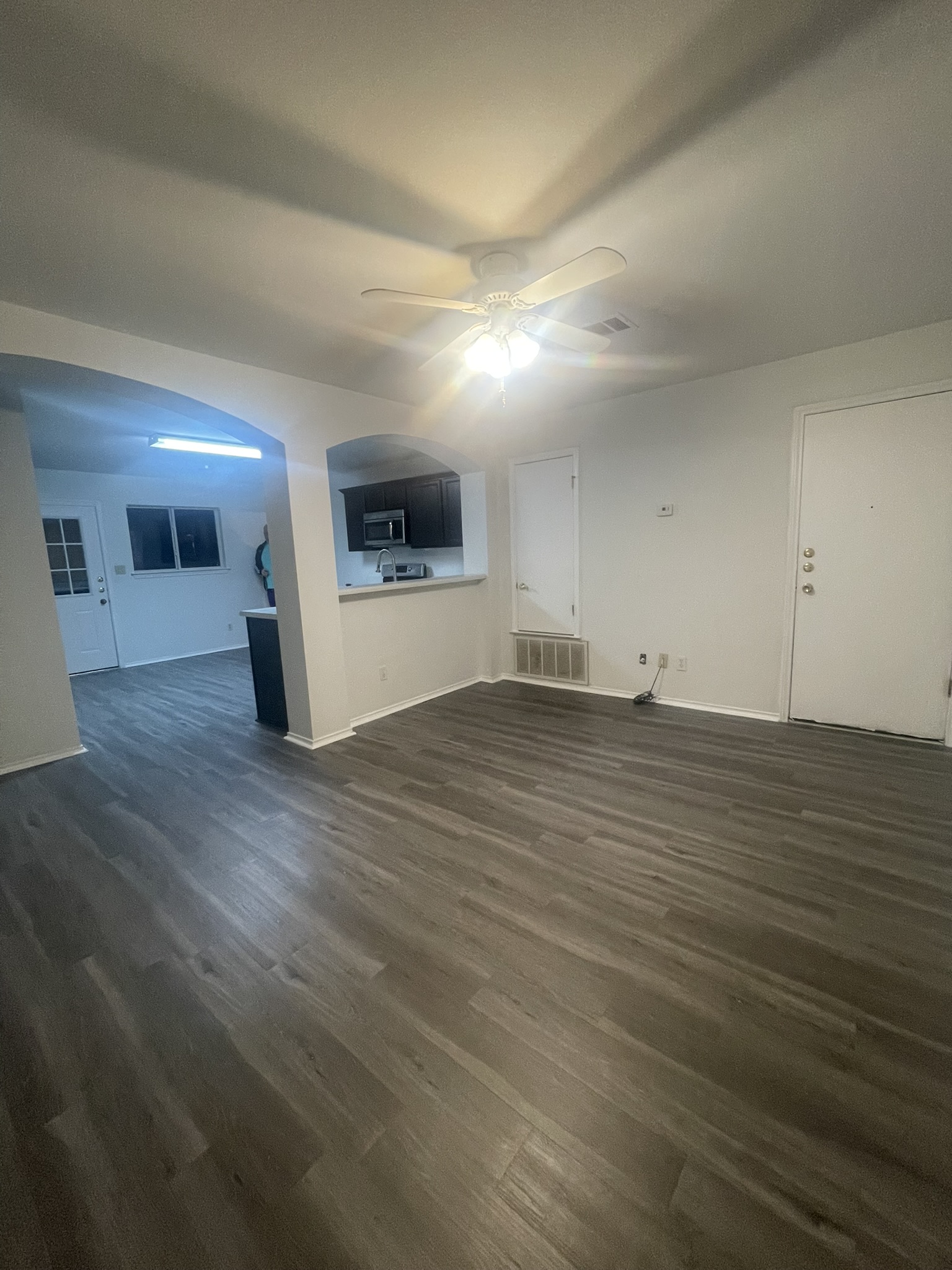221 Britni Loop Kyle, TX 78640 - Photo 20 of 20 Unfurnished living room with arched walkways, ceiling fan, and dark wood-type flooring