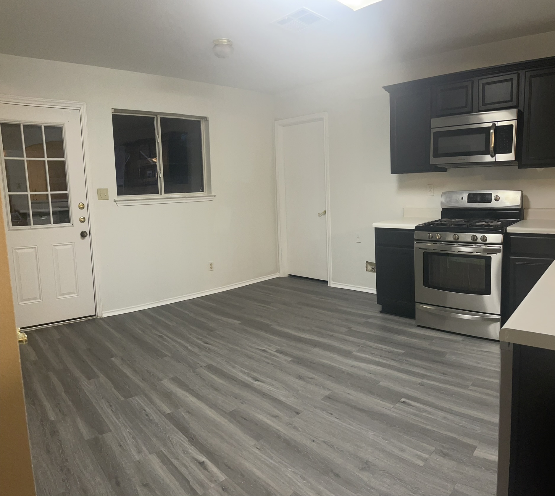 221 Britni Loop Kyle, TX 78640 - Photo 4 of 20 Kitchen with stainless steel appliances, light countertops, dark wood-style floors, and dark cabinets