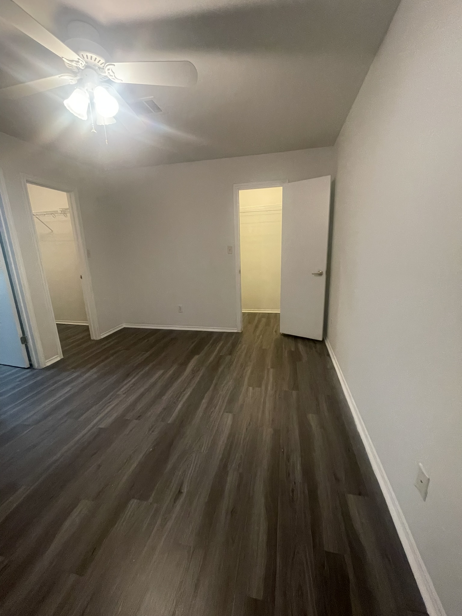 221 Britni Loop Kyle, TX 78640 - Photo 6 of 20 Unfurnished bedroom with a walk in closet, dark wood finished floors, and a ceiling fan