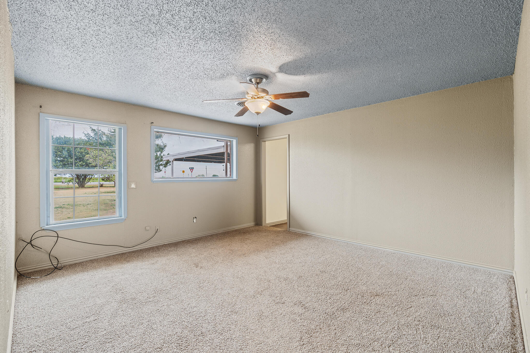 903 Highway 87 Kress, TX 79052 - Photo 8 of 26 an empty room with chandelier fan and windows