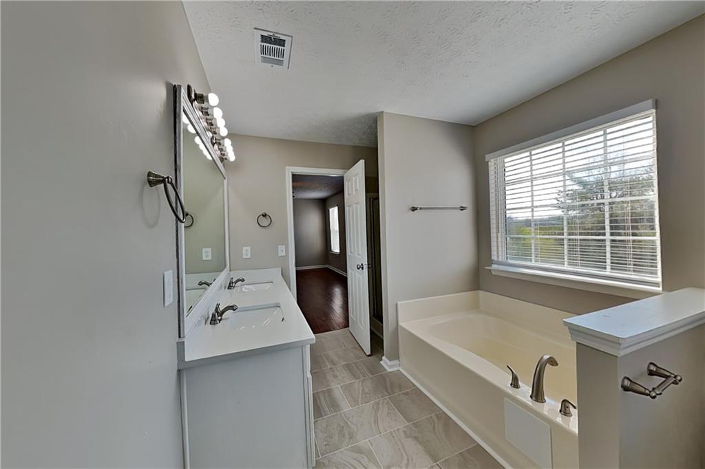 7550 Springmill Court Cumming, GA 30028 - Photo 15 of 24 a bathroom with a tub sink and mirror