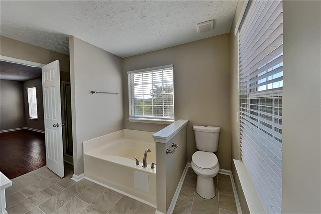 7550 Springmill Court Cumming, GA 30028 - Photo 16 of 24 a bathroom with a toilet and a shower curtain
