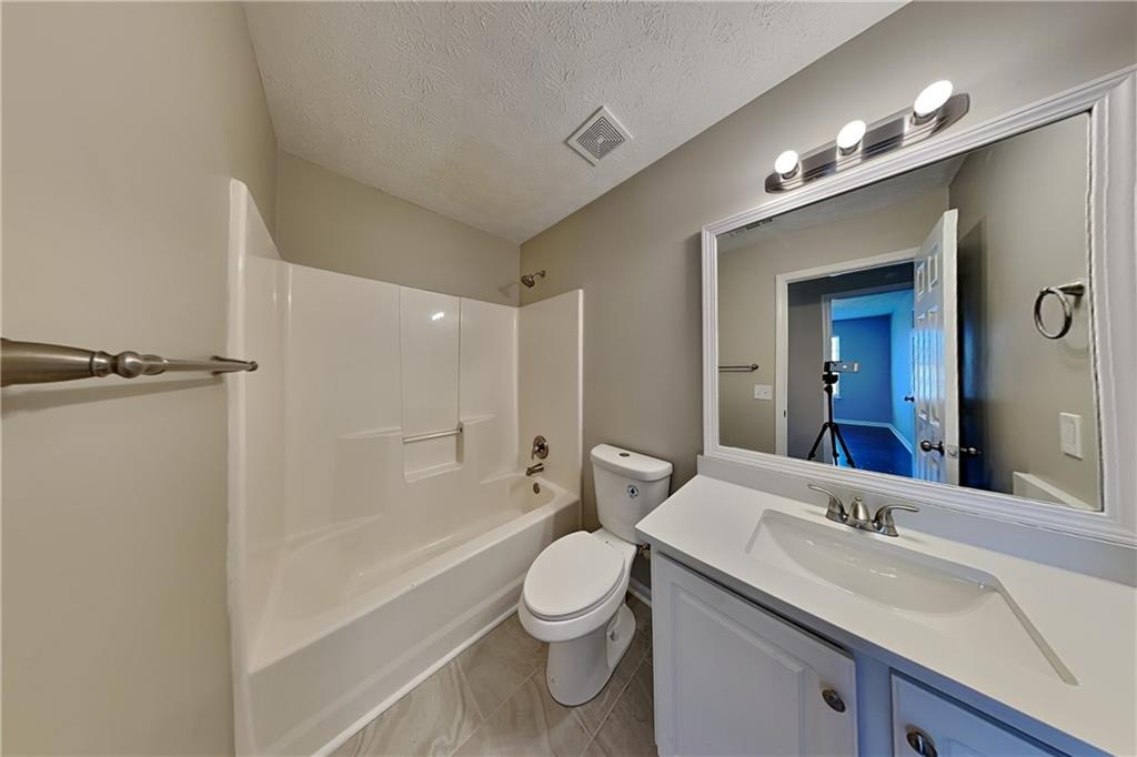 7550 Springmill Court Cumming, GA 30028 - Photo 21 of 24 a bathroom with a granite countertop sink toilet a large mirror a bathtub and shower