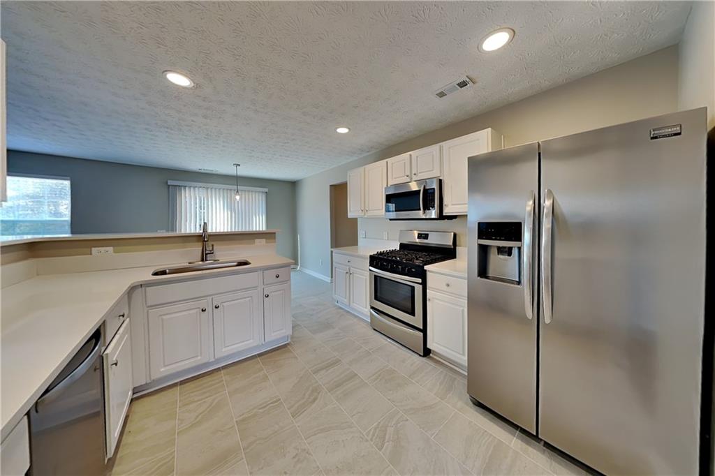 7550 Springmill Court Cumming, GA 30028 - Photo 6 of 24 a large kitchen with cabinets stainless steel appliances and a counter space