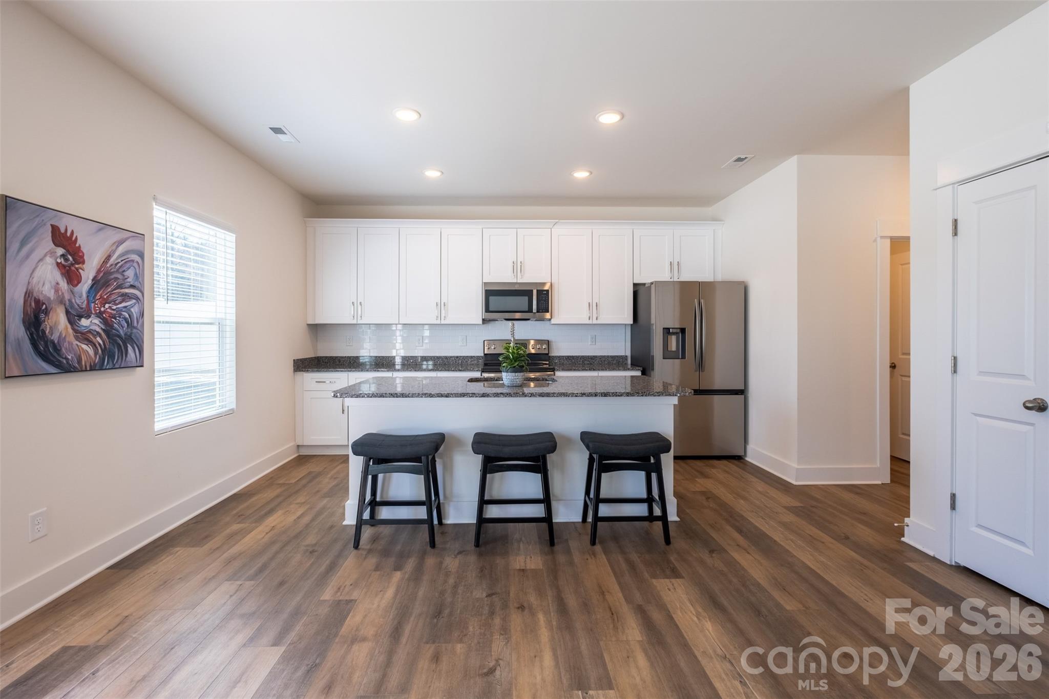220 Sugar Hill Road Troutman, NC 28166 - Photo 14 of 37 a kitchen with stainless steel appliances granite countertop a stove a refrigerator a sink a dining table and chairs with wooden floor
