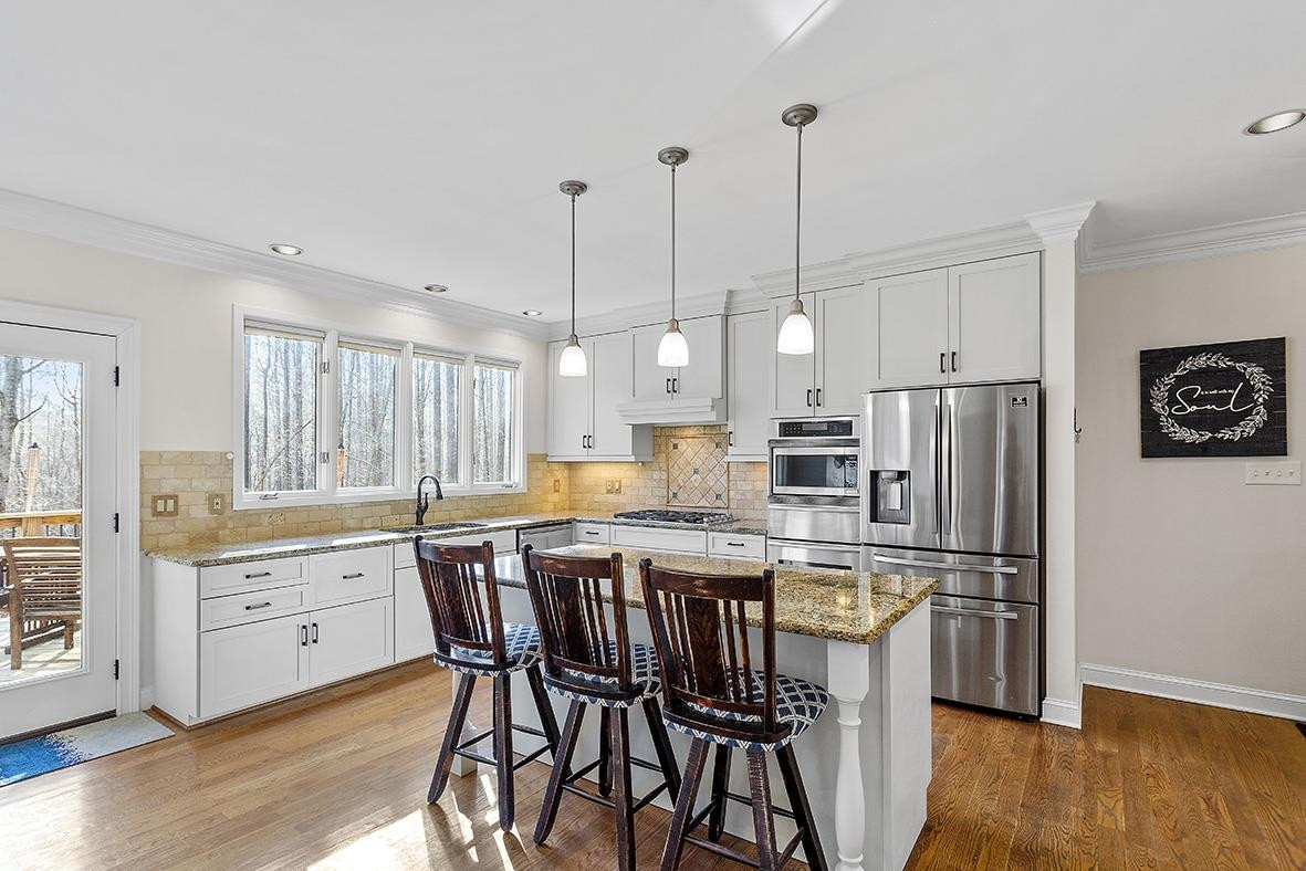 8120 Hawkshead Road Wake Forest, NC 27587 - Photo 24 of 70 a kitchen with stainless steel appliances kitchen island granite countertop a wooden floor and white cabinets