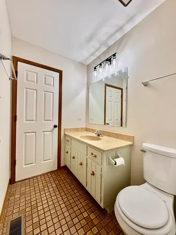 a bathroom with a granite countertop toilet sink and mirror