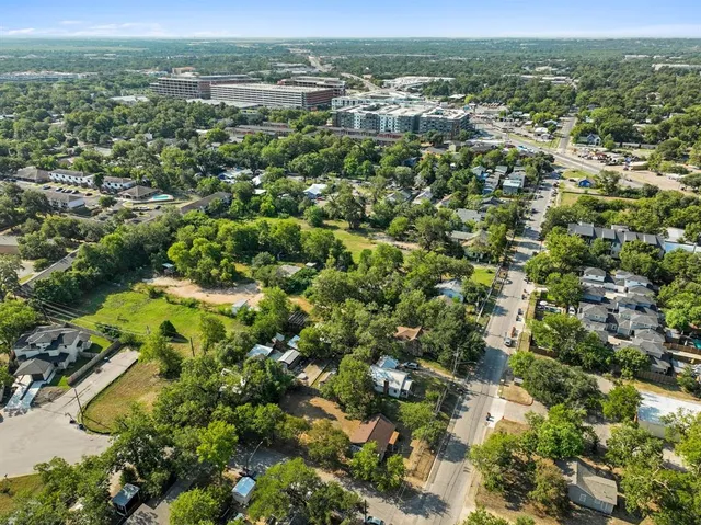 an aerial view of residential houses with outdoor space and trees
