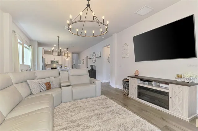 a living room with furniture a chandelier and a view of kitchen