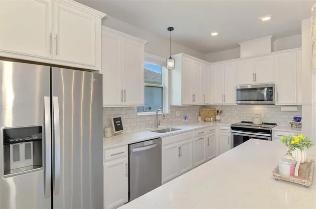 a kitchen with white cabinets and appliances