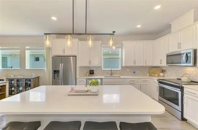 a kitchen with kitchen island stainless steel appliances a sink stove and refrigerator