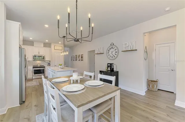 a view of a dining room and livingroom with furniture wooden floor a rug a painting and a chandelier