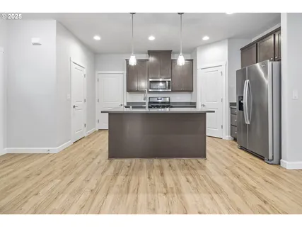 a kitchen with stainless steel appliances granite countertop a refrigerator a sink dishwasher and a wooden cabinets