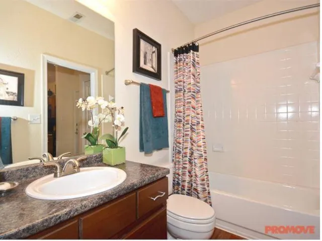 a bathroom with a granite countertop sink toilet a mirror a bathtub and shower