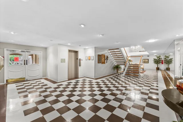 a living room with a black white checkered floor with a gaming machine and dining chairs