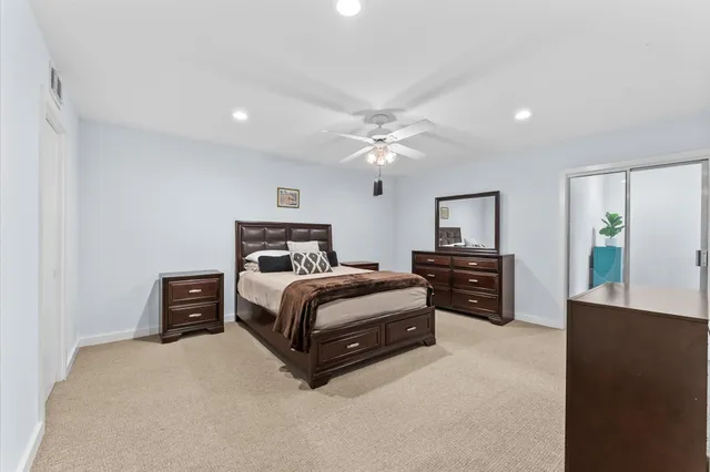 a bedroom with a bed and dresser with chair