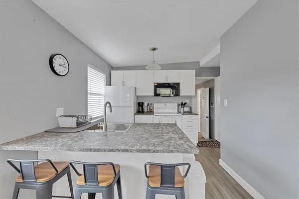 a kitchen with kitchen island granite countertop a table chairs microwave and cabinets