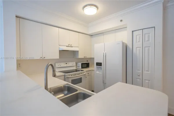 a kitchen with stainless steel appliances a refrigerator sink and white cabinets