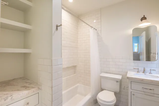 a bathroom with a granite countertop sink a toilet and shower