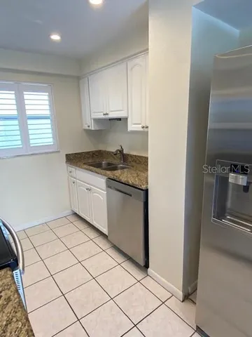 a kitchen with granite countertop white cabinets and white appliances