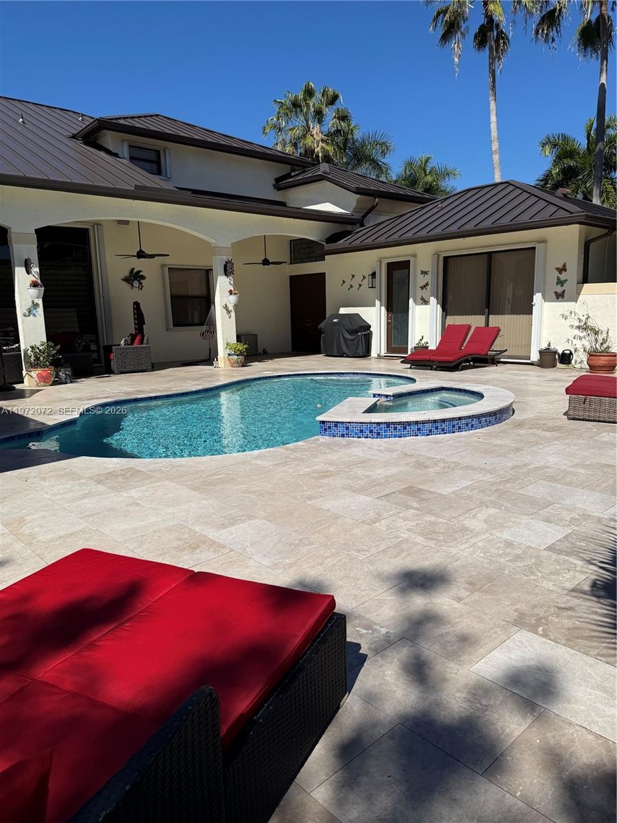 18610 Southwest 39th Court Miramar, FL 33029 - Photo 3 of 32 a view of a white house with large windows and a table and chairs under an umbrella