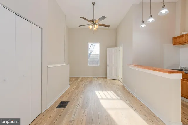 a view of a livingroom with a chandelier fan and wooden floor