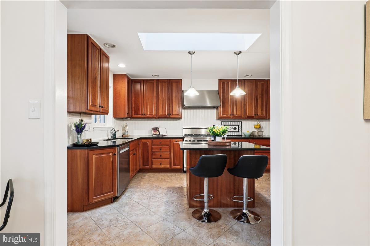 12145 Stirrup Road Reston, VA 20191 - Photo 33 of 80 a kitchen with kitchen island granite countertop wooden cabinets and a stove