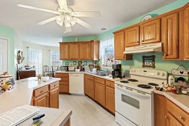 a kitchen with a stove a sink dishwasher and a refrigerator with wooden floor