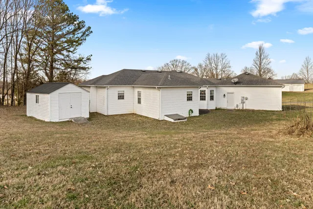 a view of a white house next to a yard with big trees