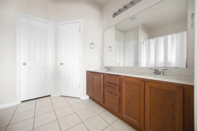 a bathroom with a double vanity sink a mirror and a bathtub